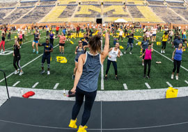 large group of people exercising in Michigan Stadium