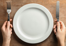 empty plate with someone holding a knife and fork