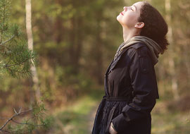 woman in nature looking up with eyes closed