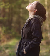 a woman in the outdoors looking up with her eyes closed