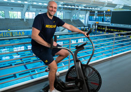 swim coach on an exercise bike infront of the pool