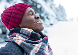 person outside in the cold with eyes closed and smiling