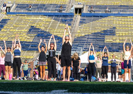people performing yoga on the Michigan Stadium field