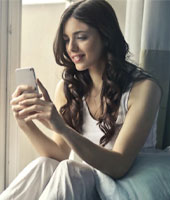 photo of woman on a phone sitting by a window